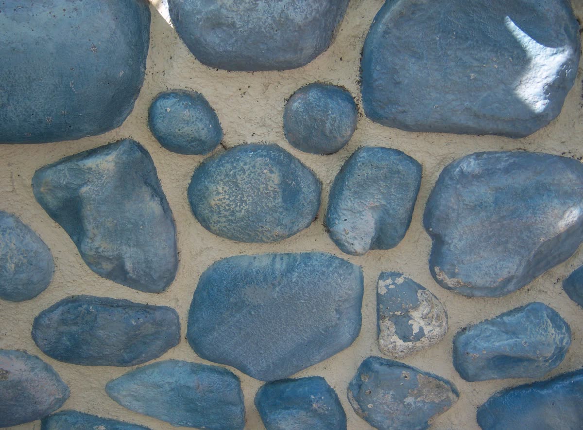 A real Hidden Mickey formed by three stones in a park wall — one large stone with two smaller round stones above forming the ears